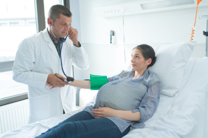 врач измеряет давление беременной в палате